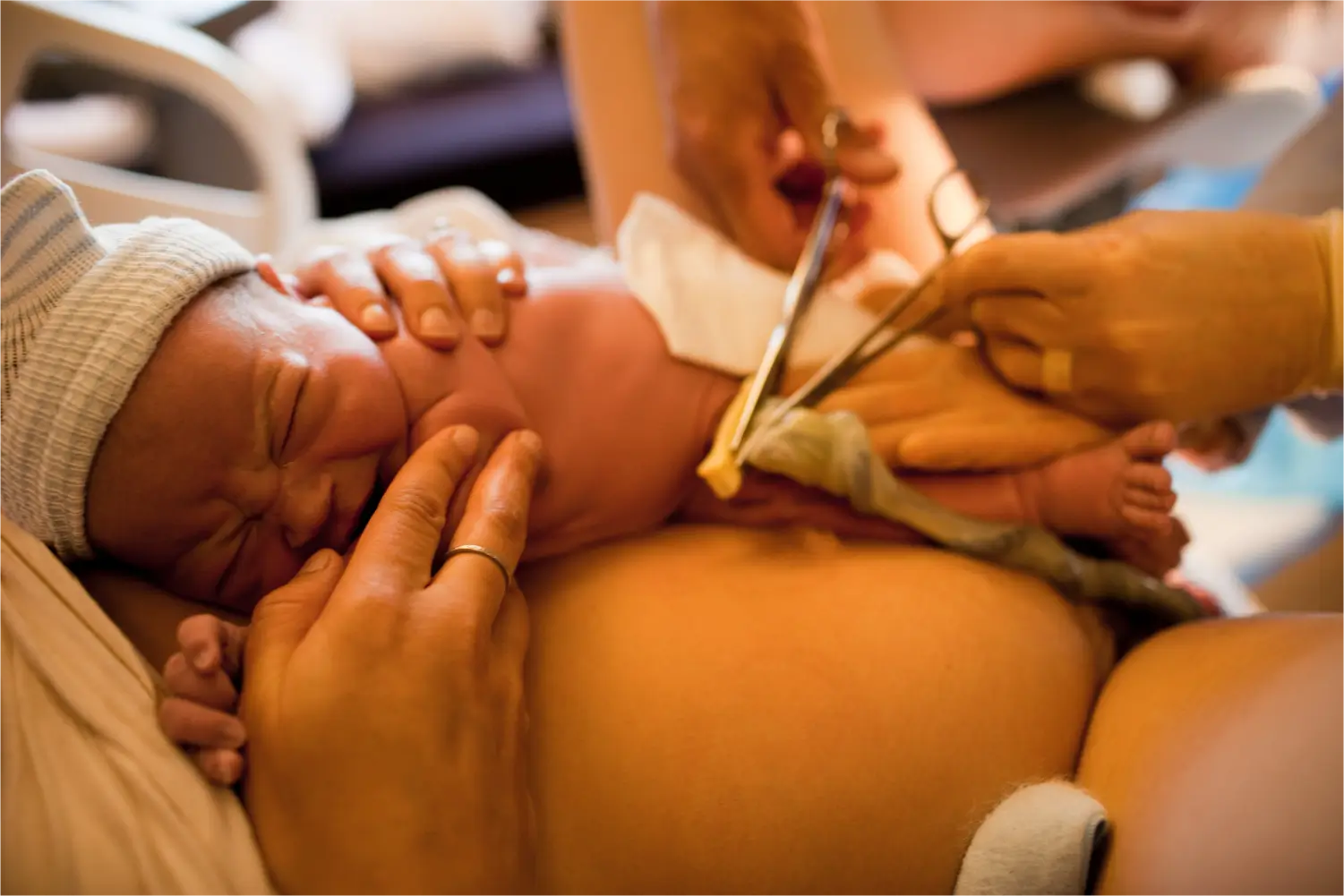 Newborn baby boy being held while the umbilical cord is cut during a vaginal birth